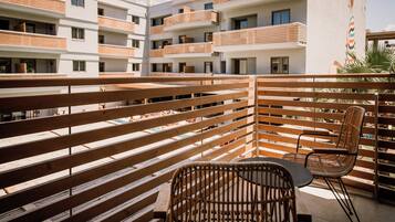 Un balcon avec des lattes en bois, une chaise en osier et une table.