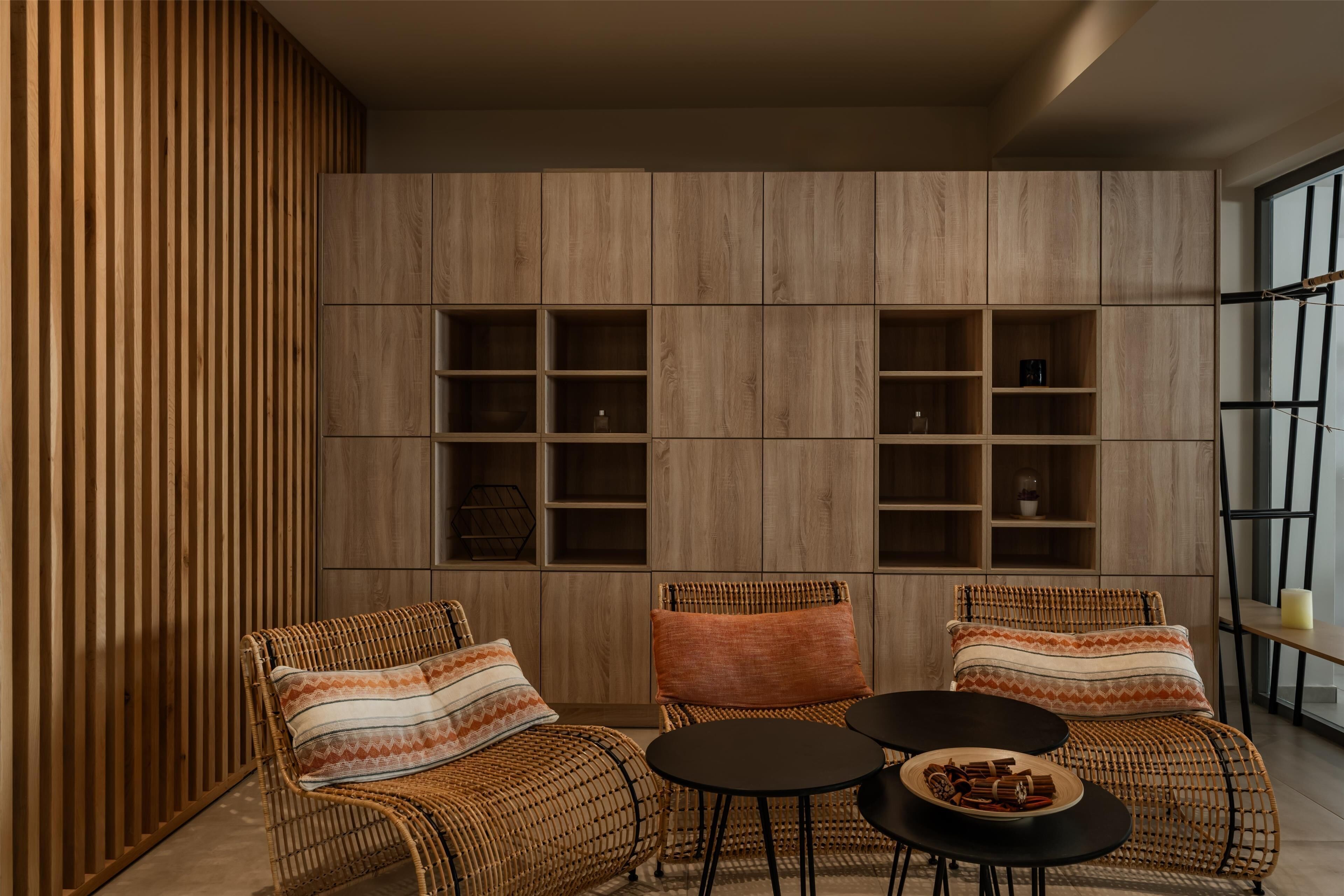 Un interior moderno con mobiliario de mimbre, una pared de madera y estanterías empotradas.