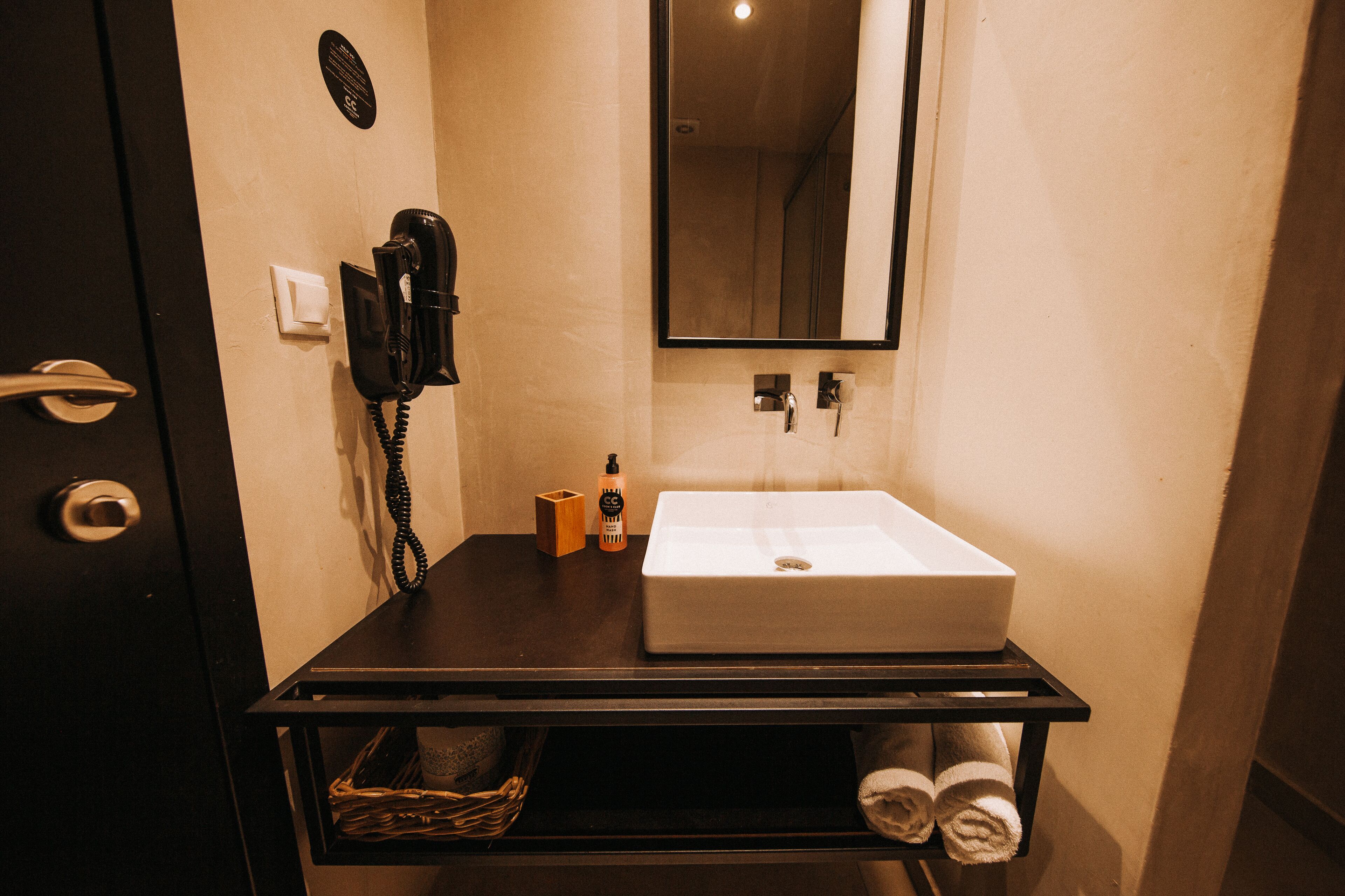 Un bagno con lavandino, asciugacapelli, telefono e asciugamani su uno scaffale.