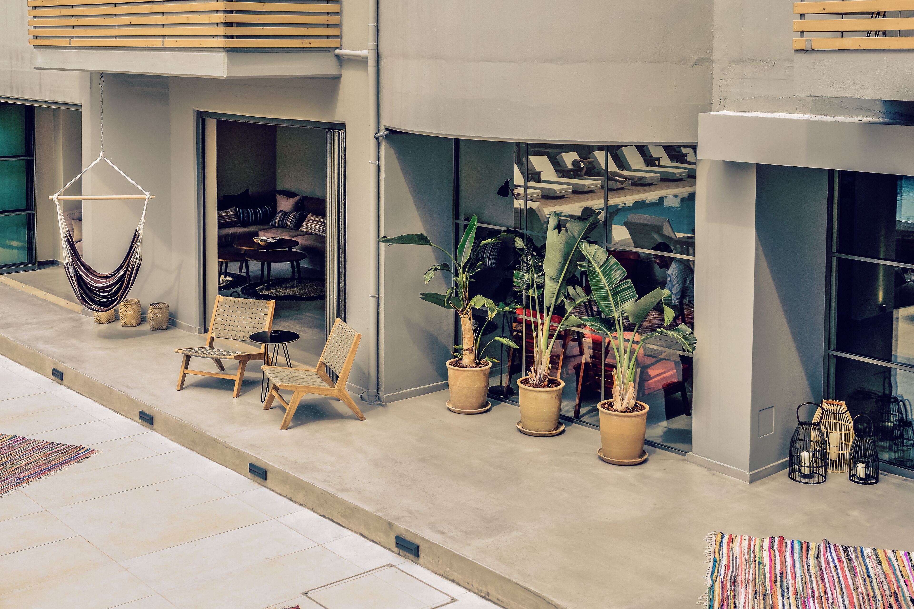 Un espace extérieur moderne aménagé avec des sièges, un hamac, des chaises et des plantes en pot.