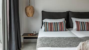 A modern bedroom with a large bed, dark curtains, a woven light fixture, and a view of the outdoors.