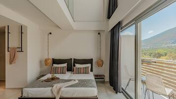 Une chambre moderne avec un grand lit, deux tables de chevet et une vue sur un balcon agrémenté d’une chaise.