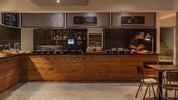A modern bar area with a wooden counter, seating, and menu boards.