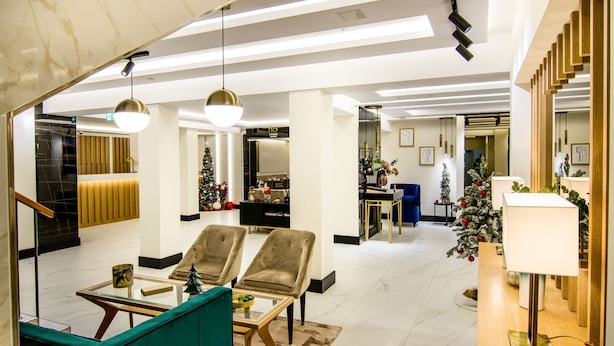 A modern hotel lobby with a seating area, a Christmas tree, and a reception desk.