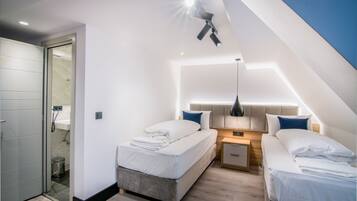 Un dormitorio moderno con dos camas, una mesita de noche y una lámpara de techo.