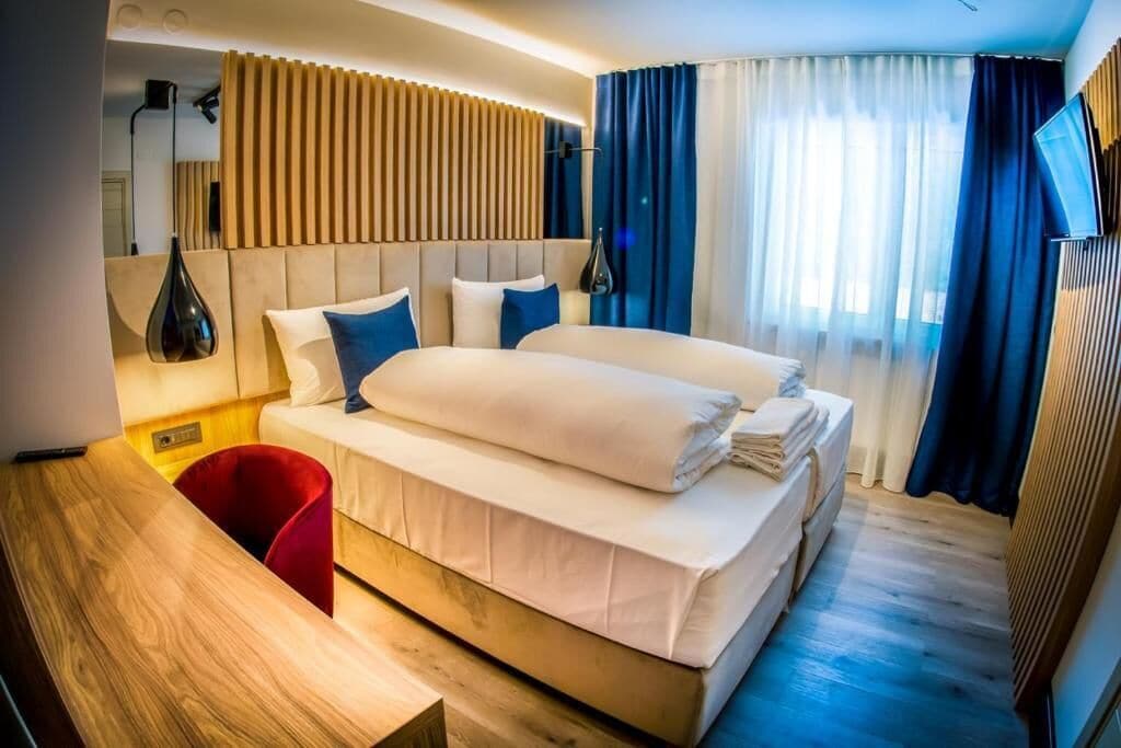 Una habitación de hotel moderna con una cama grande, un escritorio de madera y una silla roja.