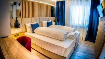 Una habitación de hotel moderna con una cama grande, un escritorio de madera y una silla roja.