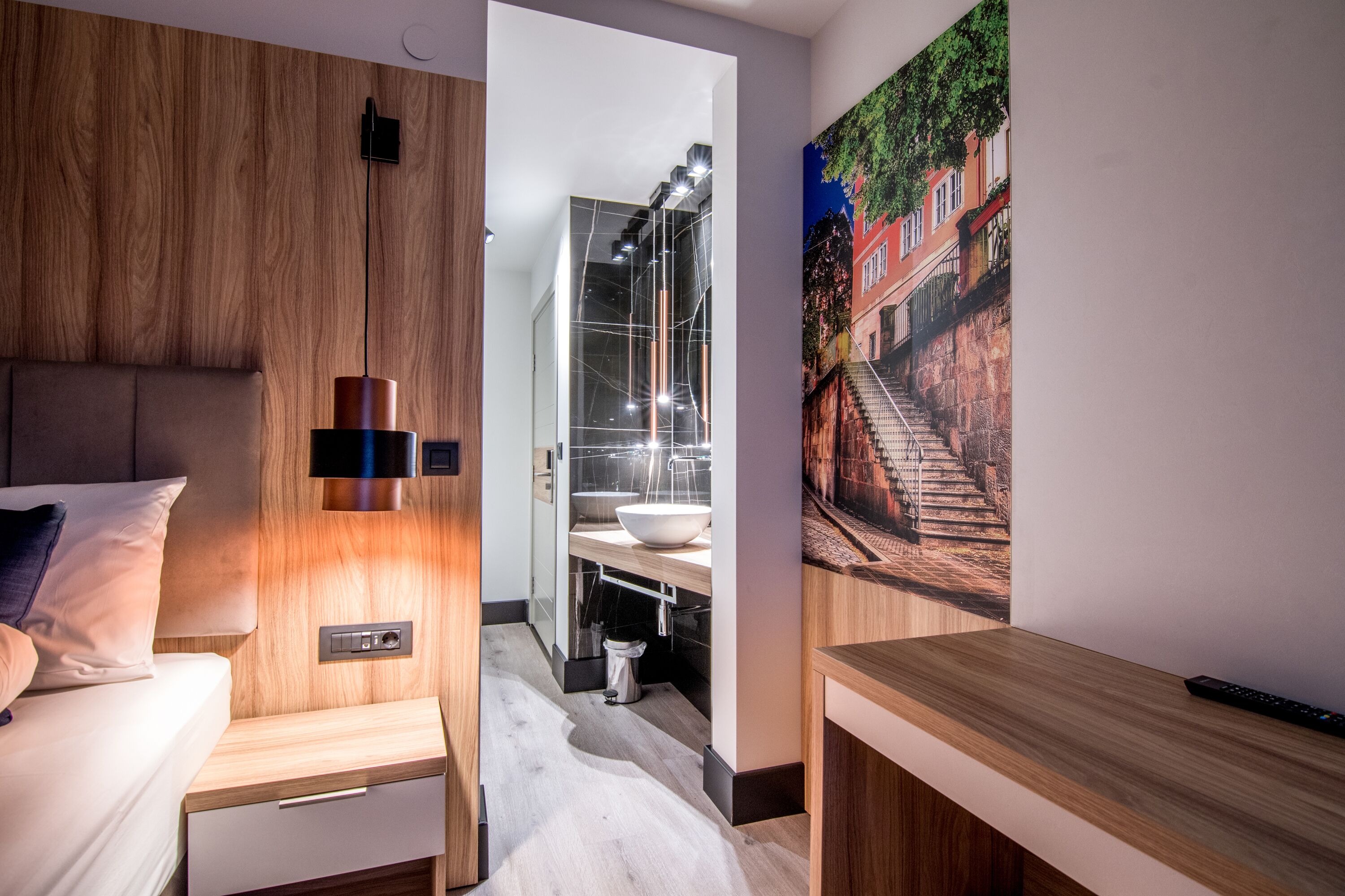 A modern hotel room with a wooden headboard, a bedside table, a nightstand, a large window, and a painting of a cityscape.