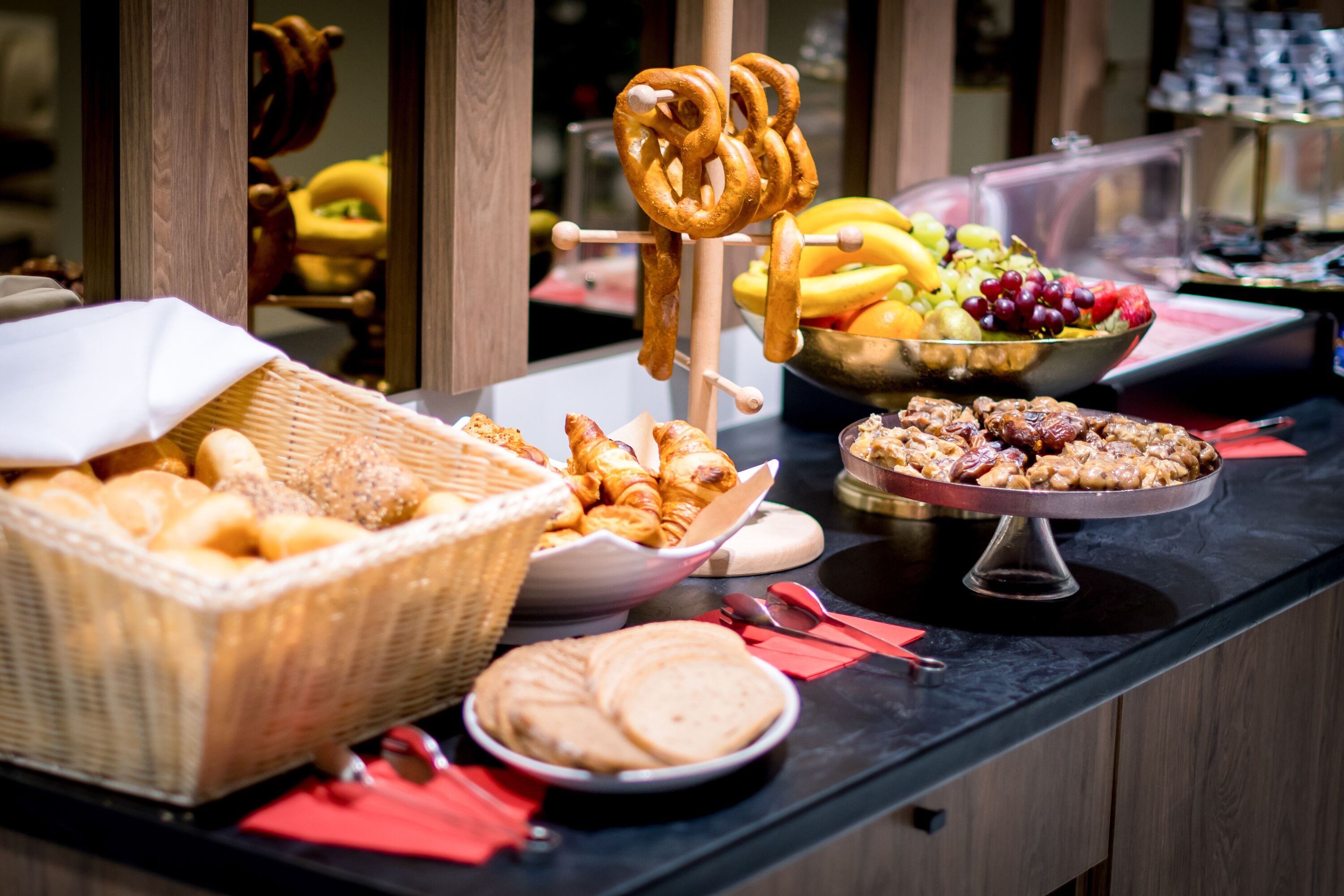 A buffet table with various food items including bread, pastries, and a fruit bowl.