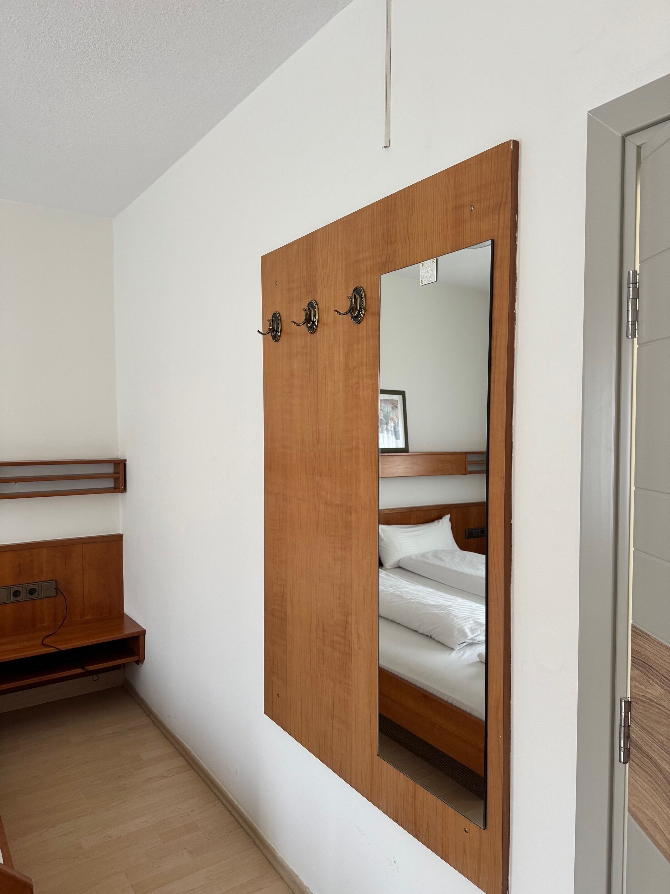 Une chambre avec une armoire en bois, un lit avec une literie blanche et une table de chevet en bois.