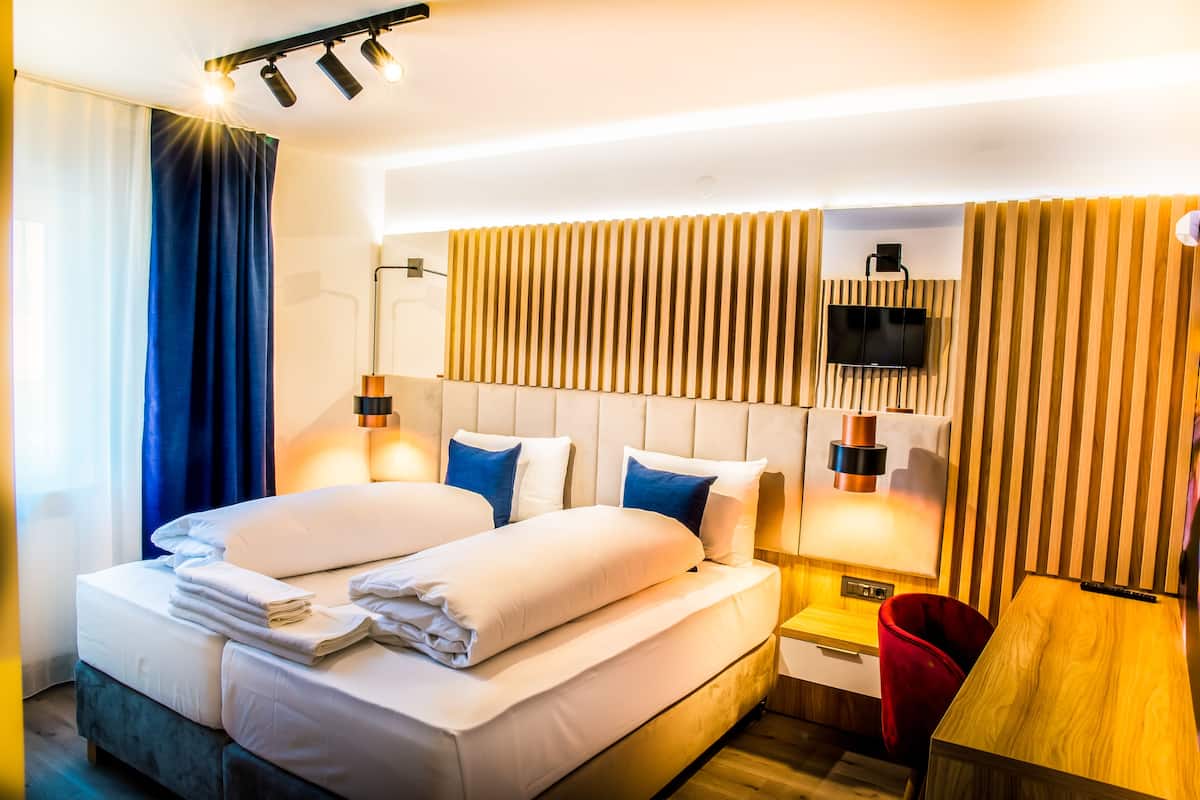 Habitación de hotel con dos camas, un televisor y un cabecero de madera.