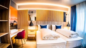 A modern hotel room with a large bed, a desk, and a chair.