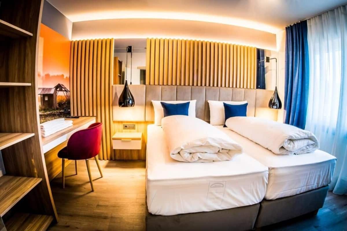 Una habitación de hotel moderna con una cama grande, un escritorio y una silla.