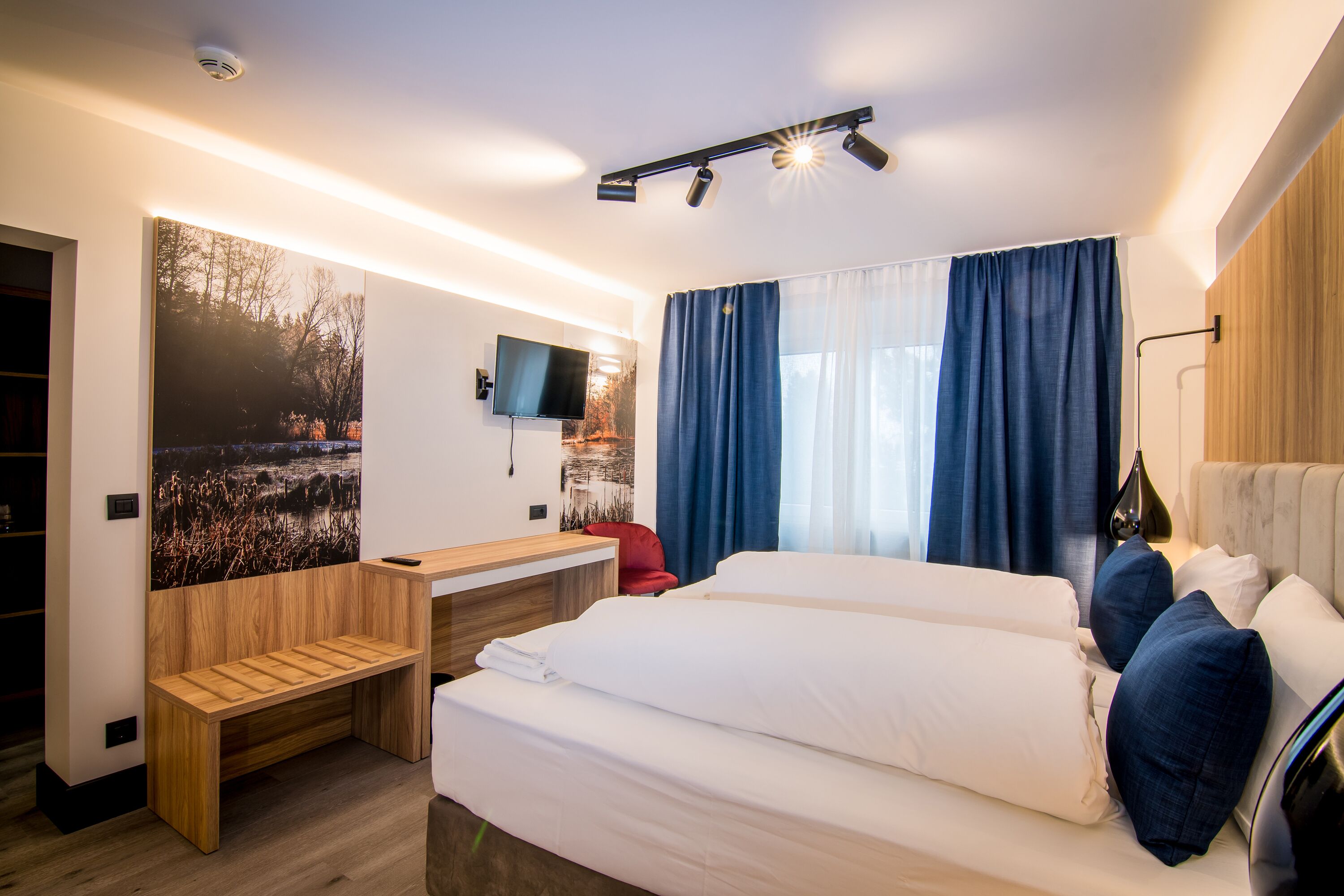 Una habitación de hotel moderna con una cama grande, un escritorio y un televisor.