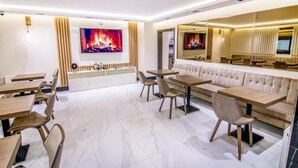 A modern dining area with a fireplace, seating arrangements, and a large mirror reflecting the space.
