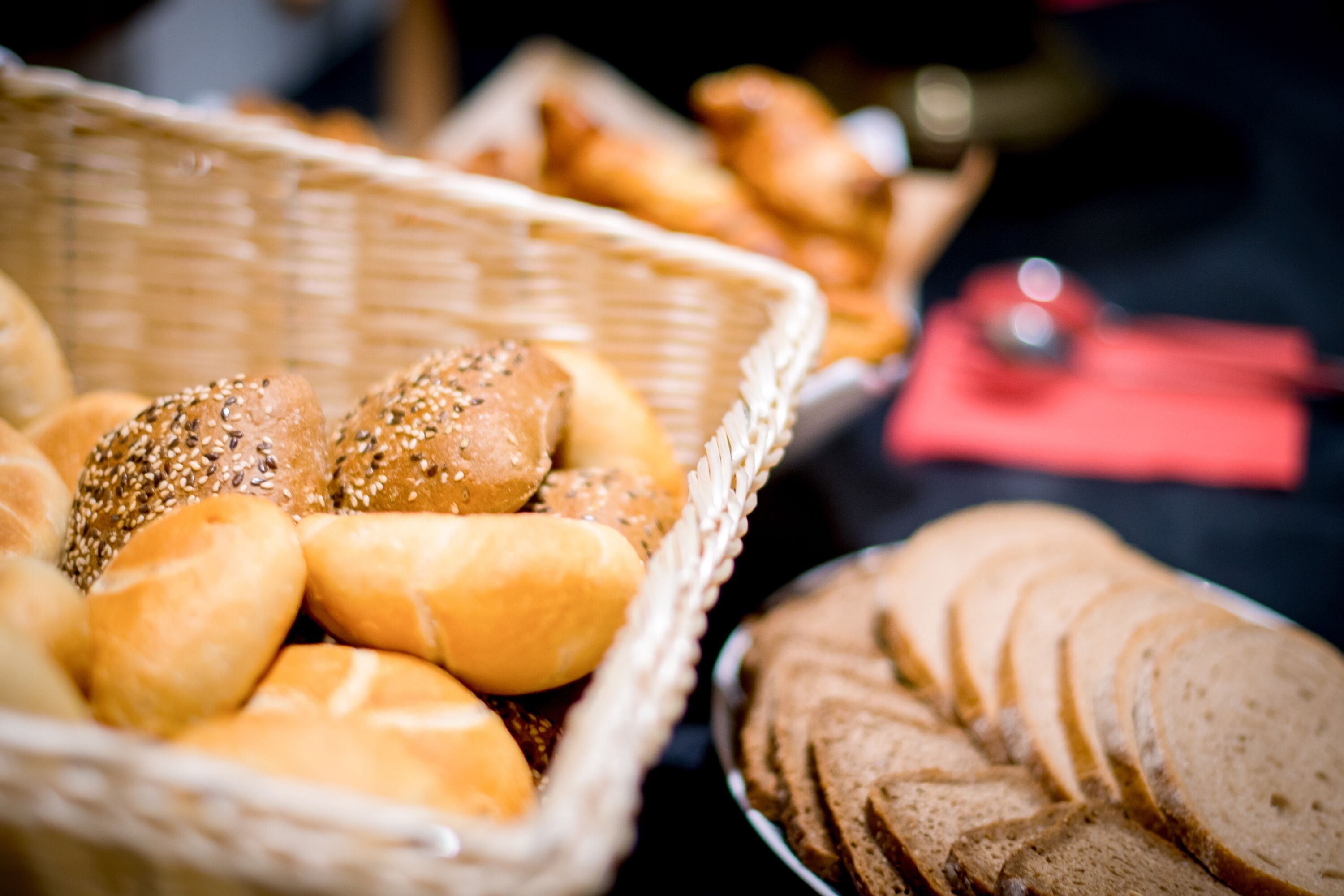 Ein Korb mit verschiedenen Brotsorten und Brötchen, darunter Sesam- und normale Sorten.