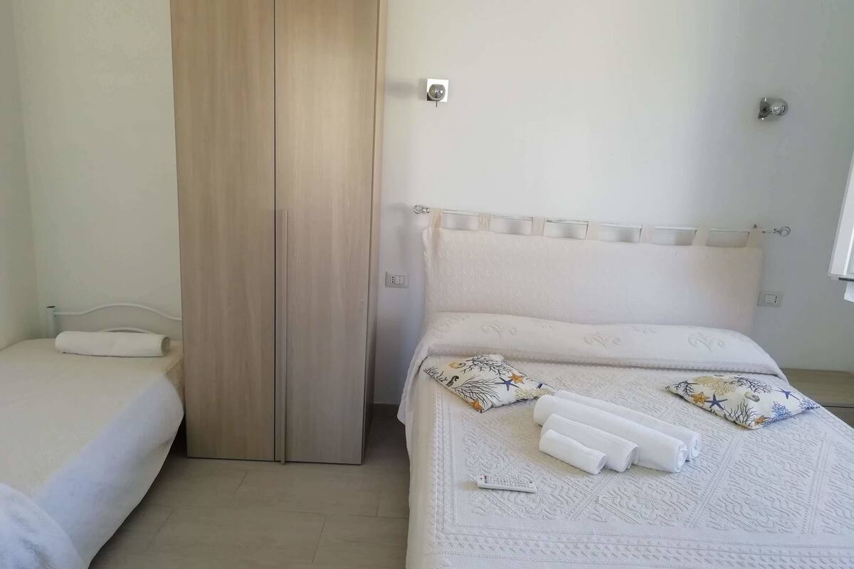A bedroom with two beds, a wooden wardrobe, and a patterned bedspread.