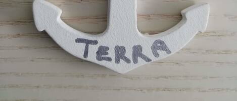 Eine weiße, ankerförmige Dekoration mit dem Wort "TERRA".