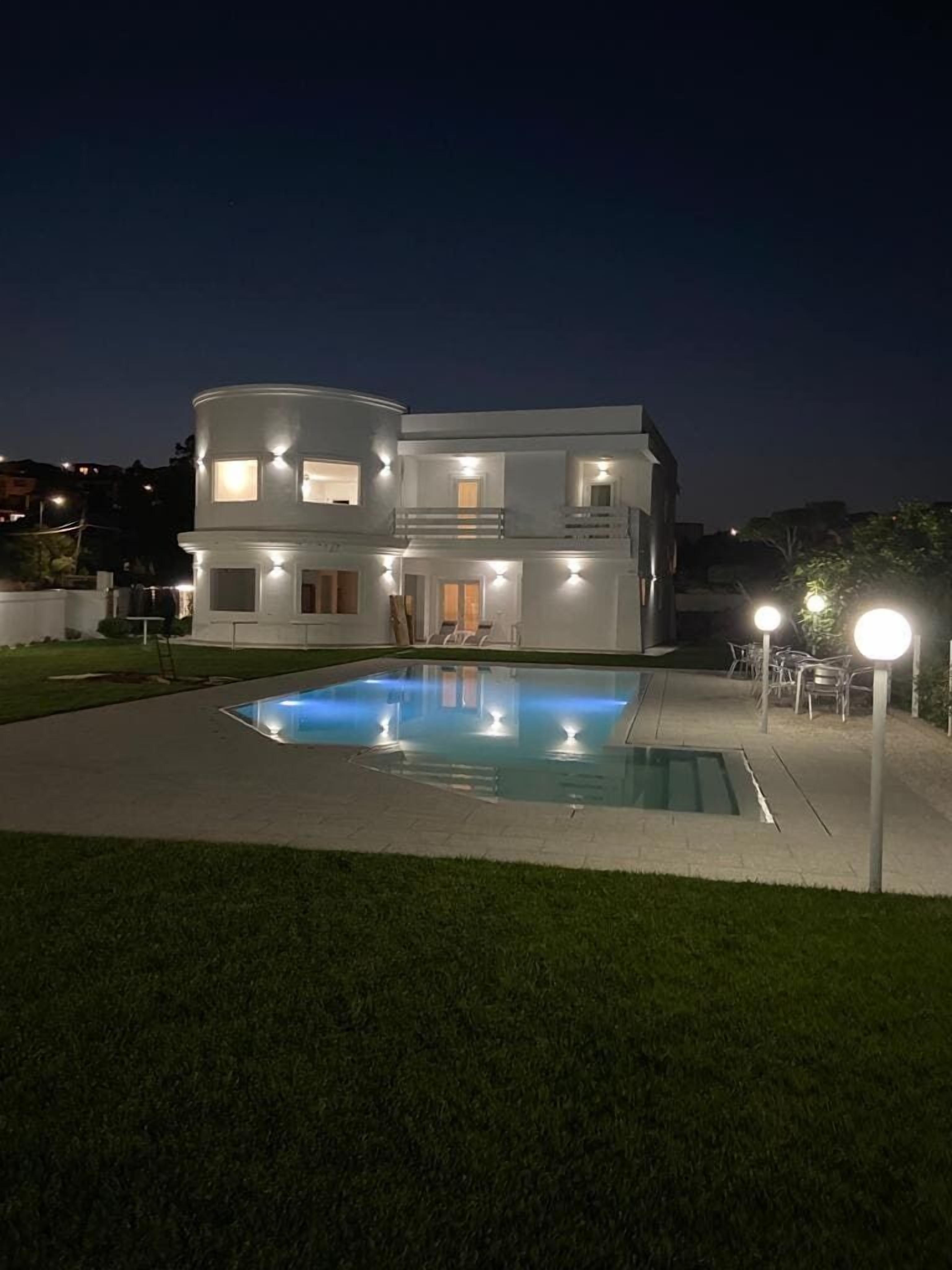 Una casa moderna de dos pisos con una piscina al frente.