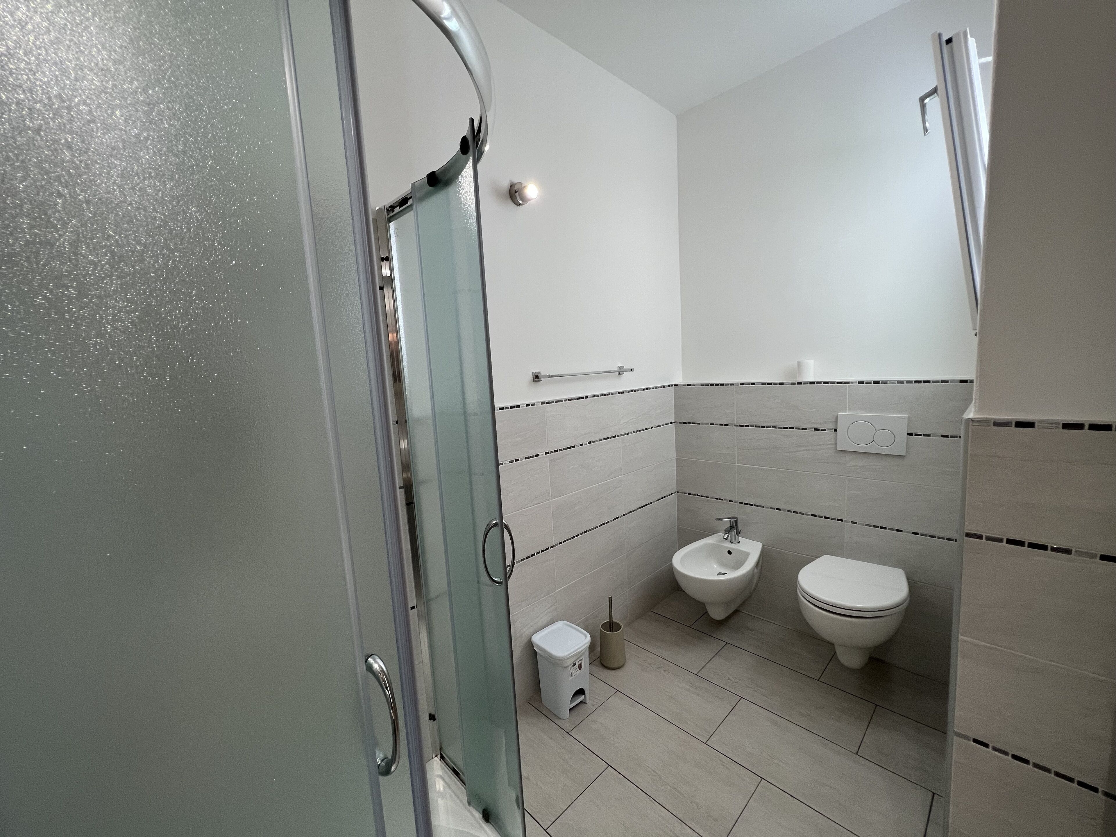 Une salle de bain moderne avec une douche à parois de verre, un bidet et des toilettes.