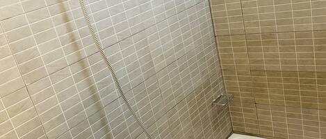 A bathroom with a bathtub, a shower head, and tiled walls.