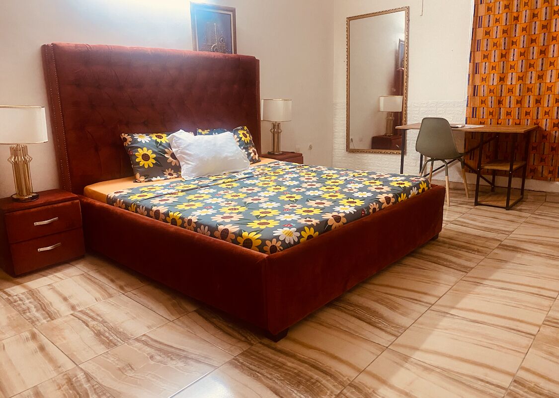 Quarto com uma cama grande, uma escrivaninha e uma cadeira.