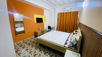 Une chambre d’hôtel équipée d’un lit, d’un bureau, d’une chaise, d’un miroir et d’une télévision.