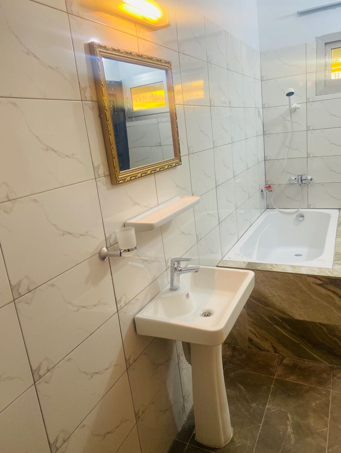 A bathroom with a sink, mirror, and bathtub.
