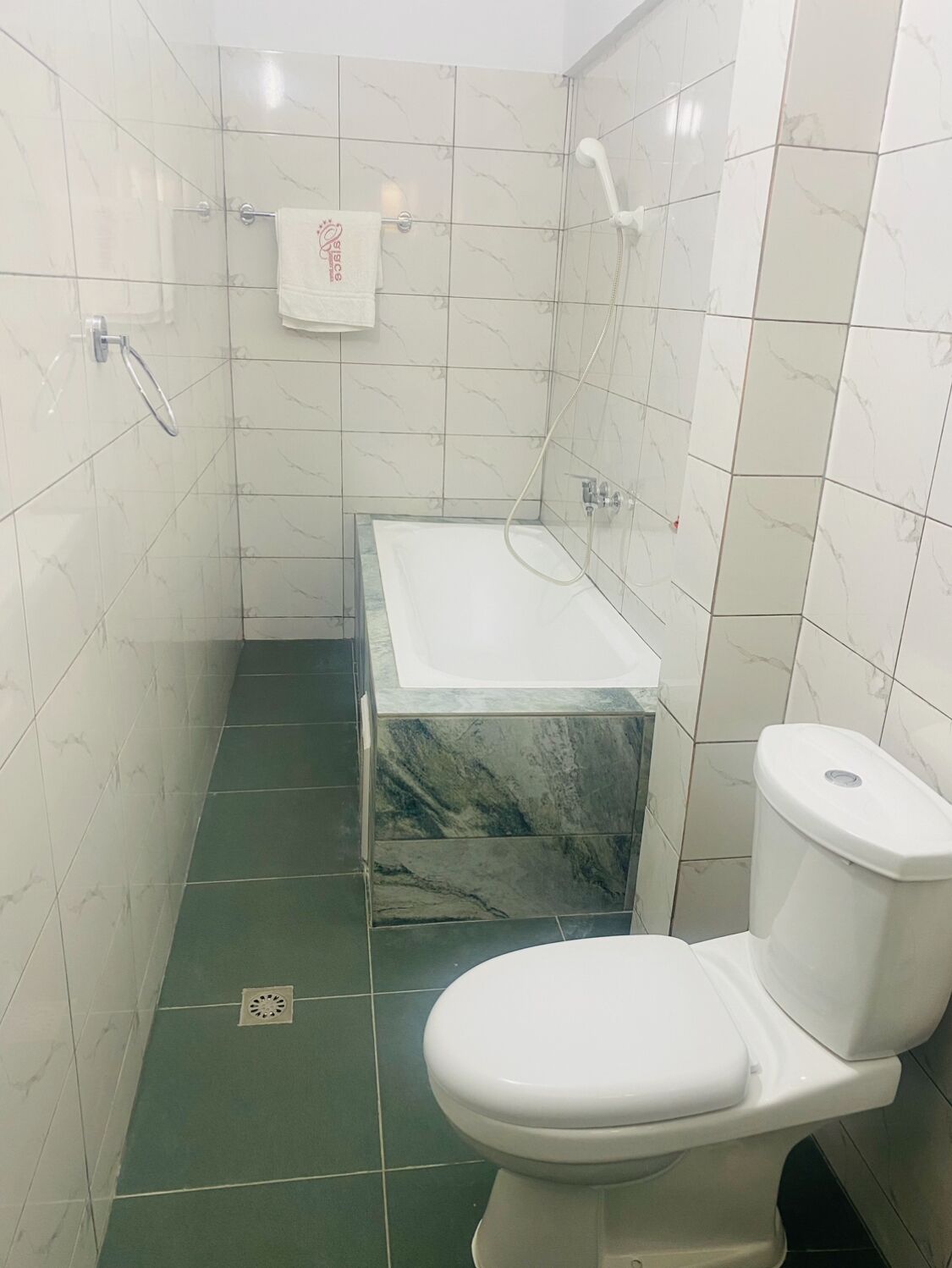 Een badkamer met toilet, een douchecabine van glas en een vloer van marmer.
