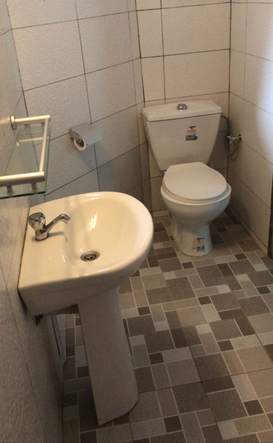 A bathroom with a white sink, toilet, and tiled floor.