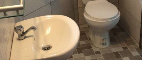 A bathroom with a white sink, toilet, and tiled floor.