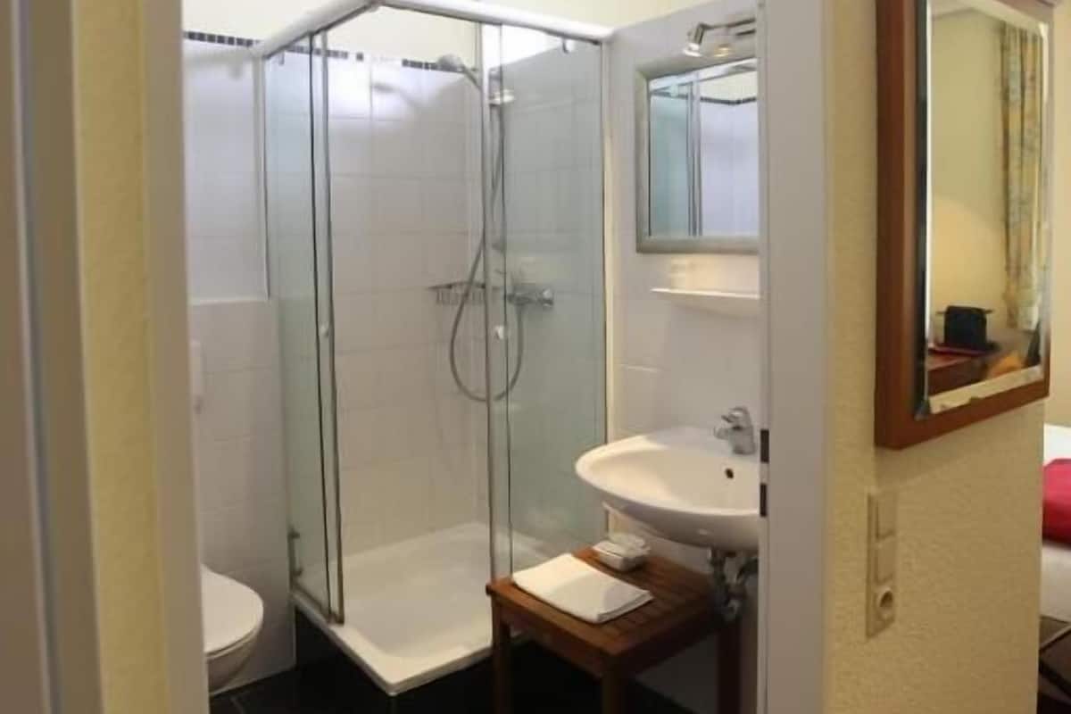 Een moderne badkamer met een douchecabine van glas, een wastafel en een spiegel.