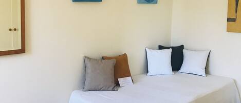 A bedroom with a large bed, a wooden floor, and two wall-mounted paintings.