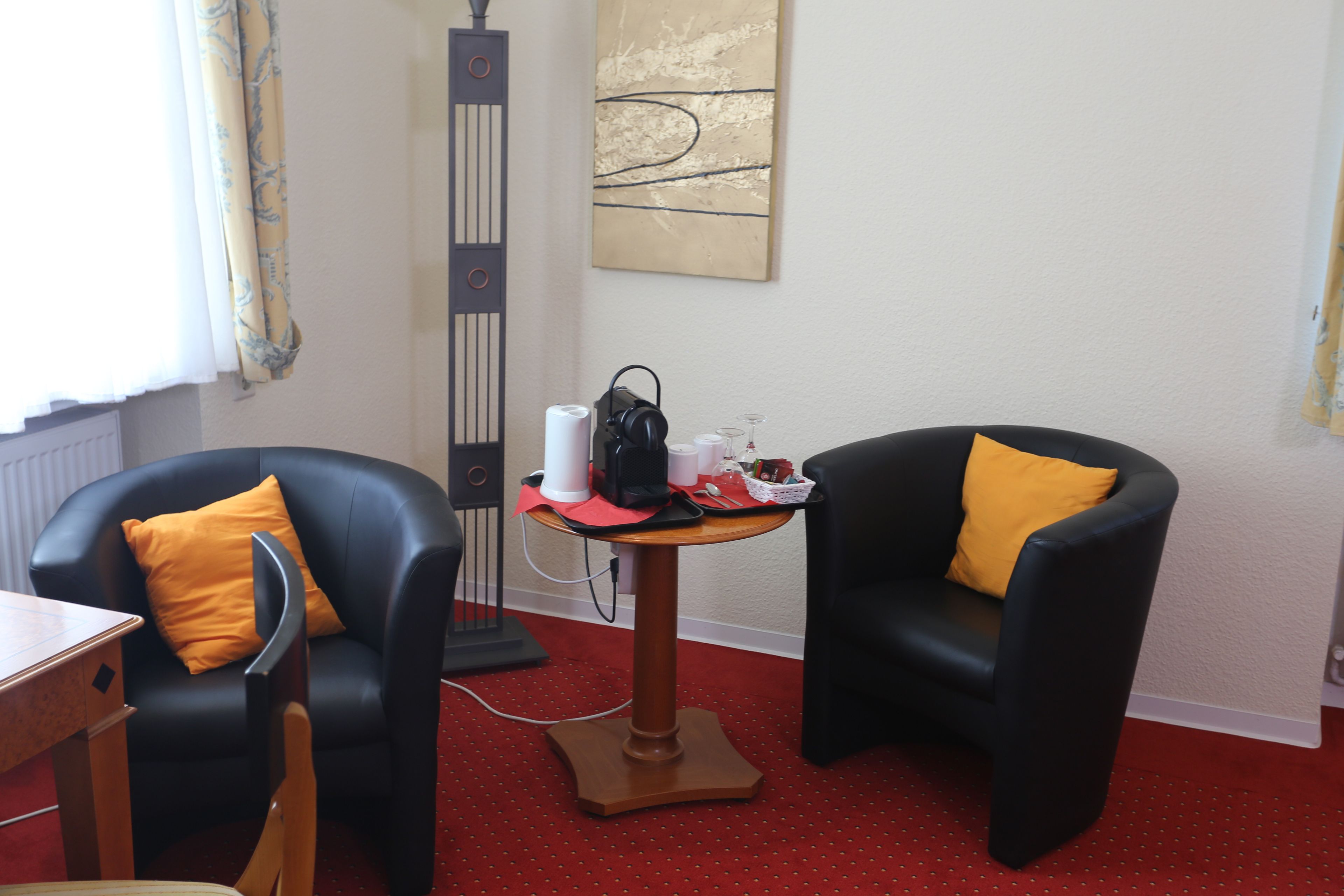A room with two black leather chairs, a small wooden table, and a standing lamp.