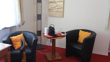 A room with two black leather chairs, a small wooden table, and a standing lamp.
