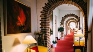 Un vestíbulo de hotel con alfombra roja, arcos de ladrillo y un sofá amarillo.