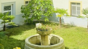 Un patio con una fuente central, rodeado de césped y árboles pequeños.