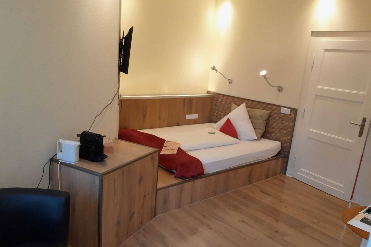 Een kleine kamer met een bed, een bureau en een stoel.