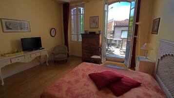 Une chambre à coucher avec un lit, un bureau, une chaise, une télévision et une fenêtre.