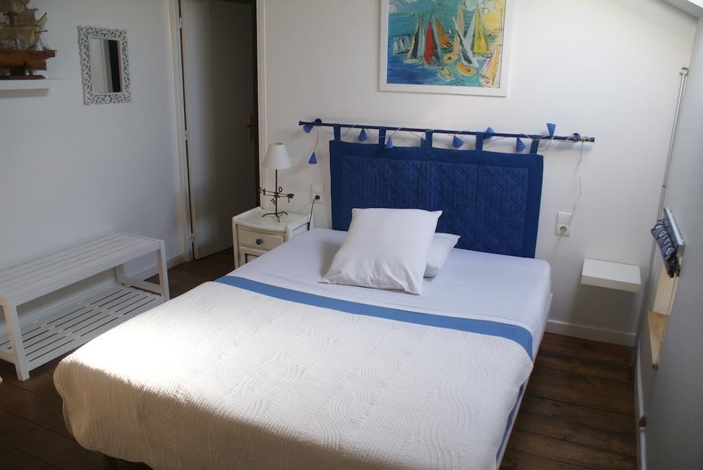 Une chambre à coucher bien rangée, avec un lit, une table de chevet et un tableau accroché au mur.