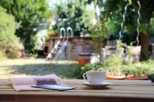 Una mesa de madera con un libro, un teléfono inteligente y una taza blanca sobre un plato.
