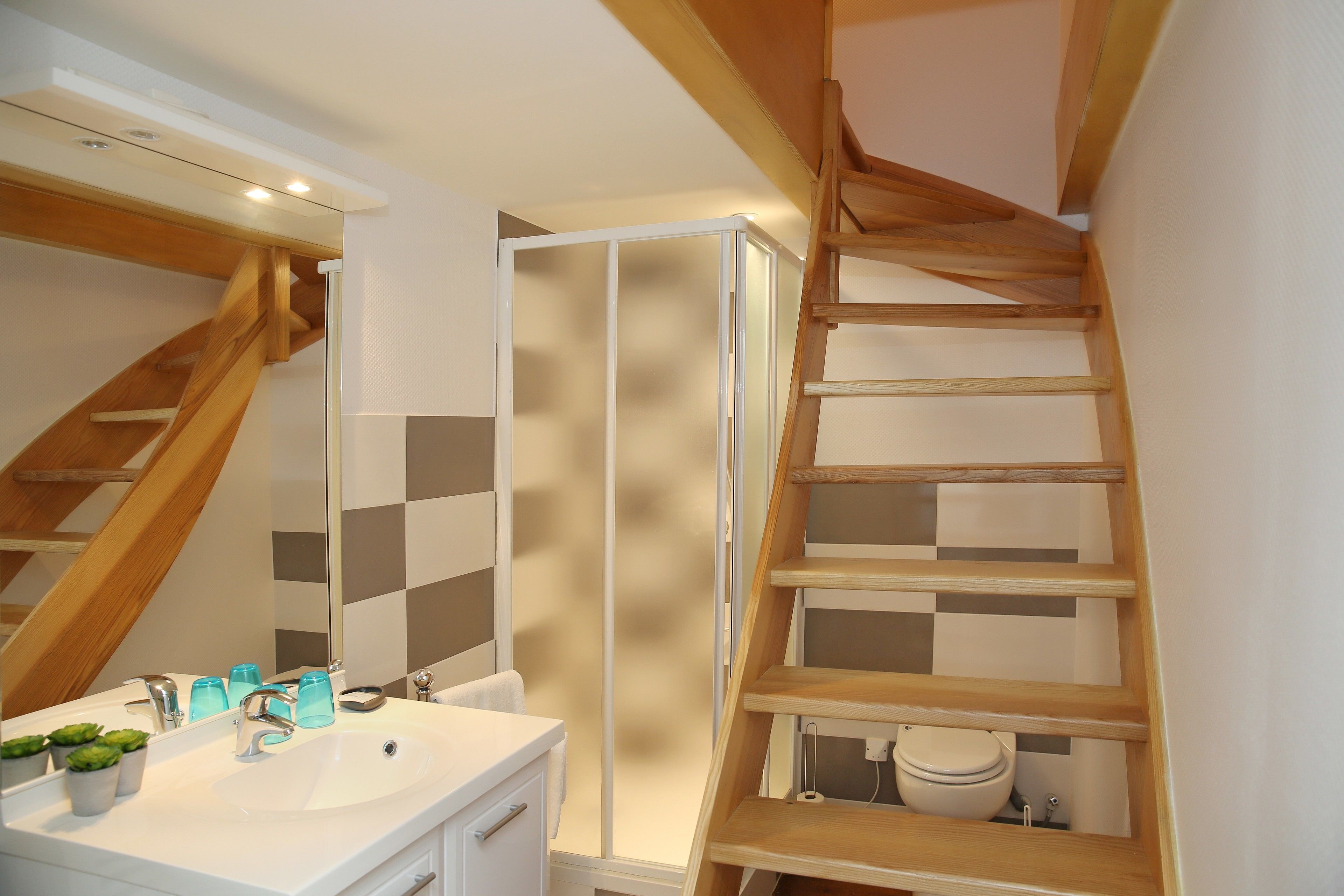 A bathroom with a white sink, mirror, and wooden shelving unit.
