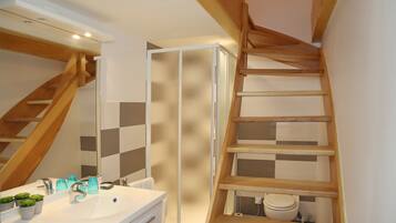 A bathroom with a white sink, mirror, and wooden shelving unit.