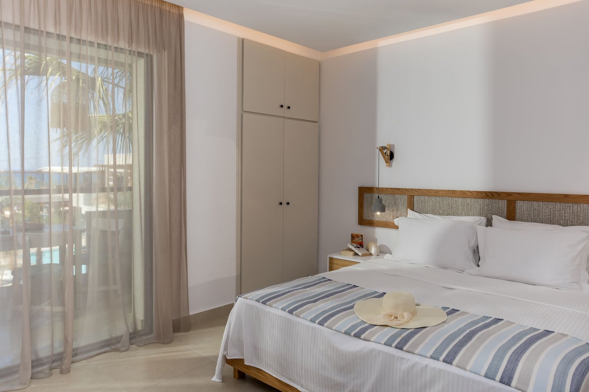 Ein Hotelzimmer mit Bett, Nachttisch, Lampe und Kleiderschrank.