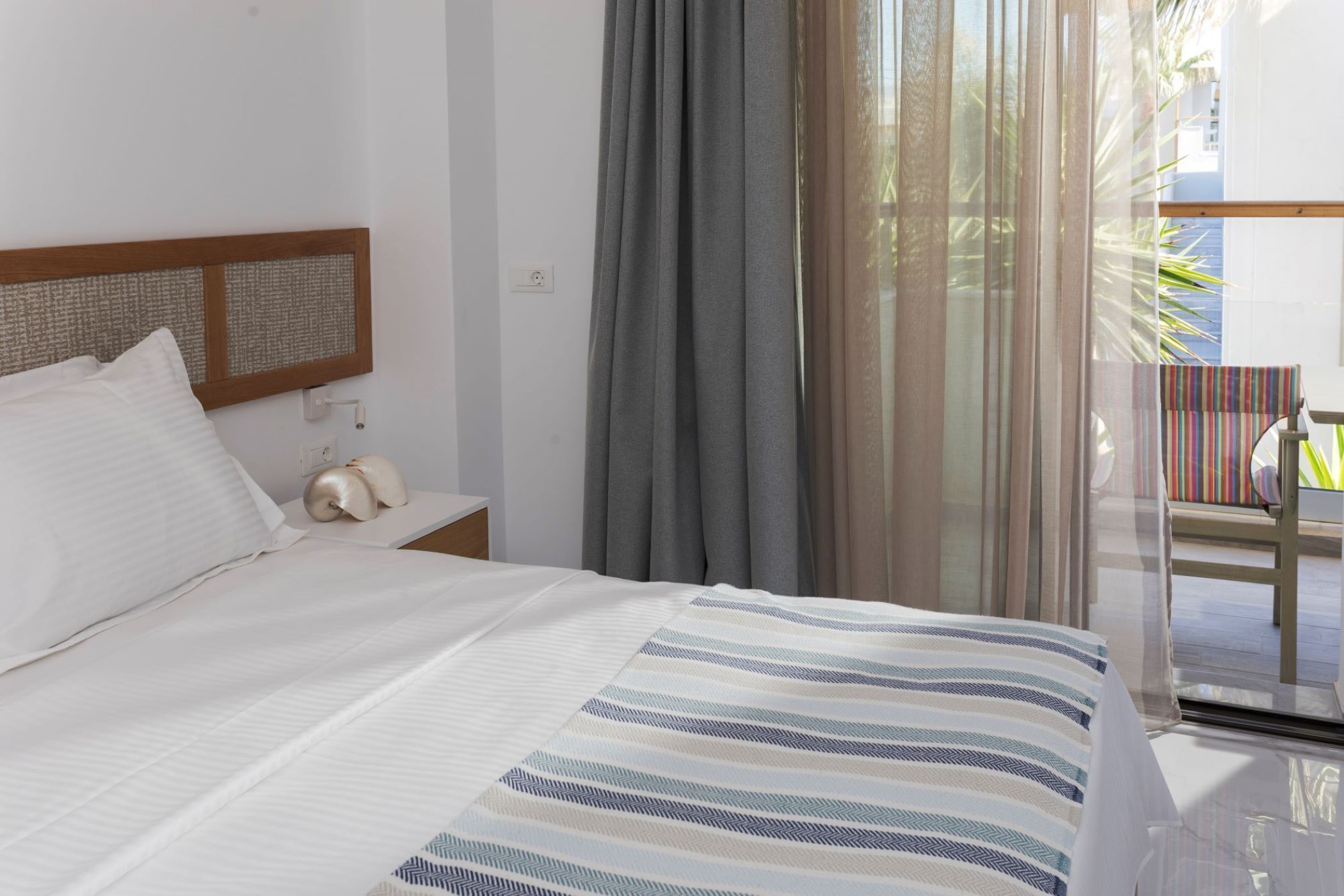 Habitació d'hotel amb llit, una tauleta de nit, finestra amb cortines i vista a l'exterior.