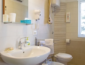 Ein Badezimmer mit Waschbecken, Toilette, Handtuchhalter und Duschbereich.