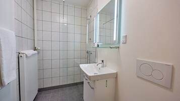 Un baño moderno con ducha, lavamanos y espejo.