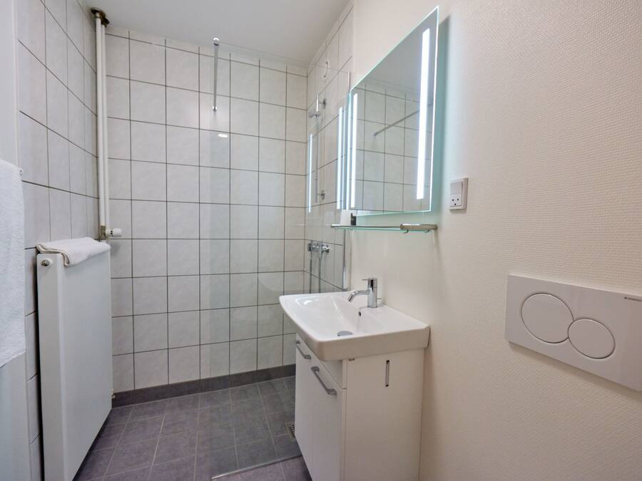 Un baño moderno con ducha, lavamanos y espejo.