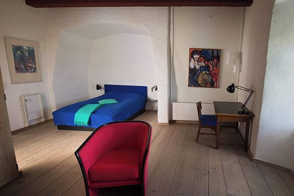 A room with a bed, a desk, a chair, and a window.