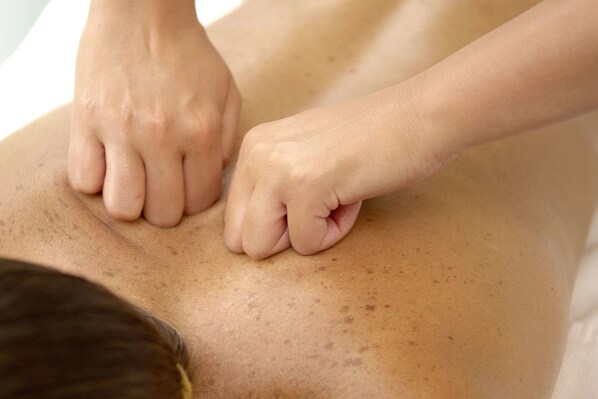 A close-up of hands performing a massage on a person's back.